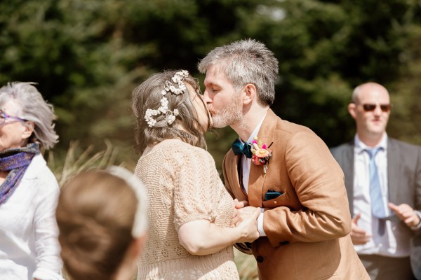 Groom kisses bride as they hold hands