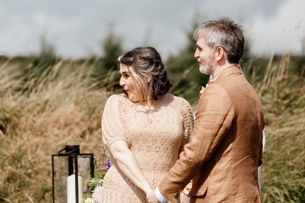 Bride looks over her shoulder as she holds grooms hands