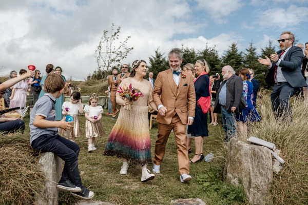 Bride and groom walk from ceremony guests clapping in background