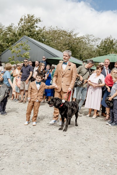 Black Labrador dog on a lead held by groom and son