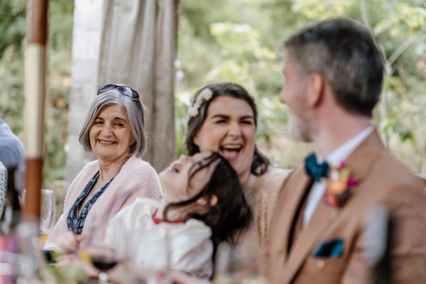 Bride and groom laugh at table with little girl laughing too