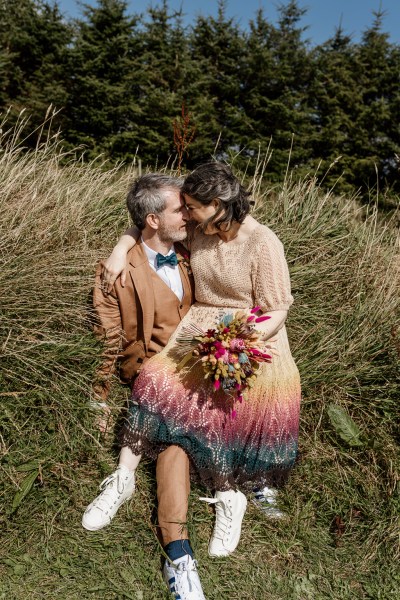 Bride and groom kiss lying in the hay on farm forest setting looking at each other