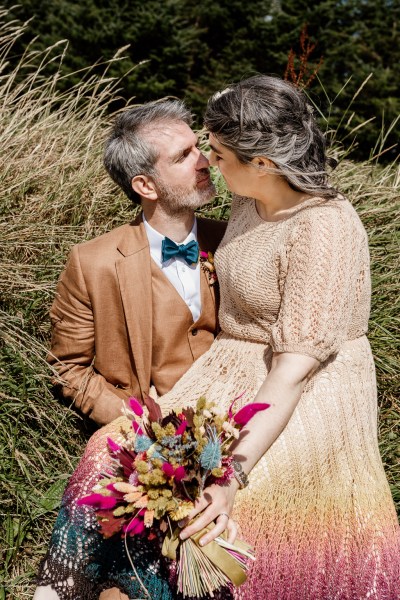 Bride and groom kiss lying in the hay on farm forest setting