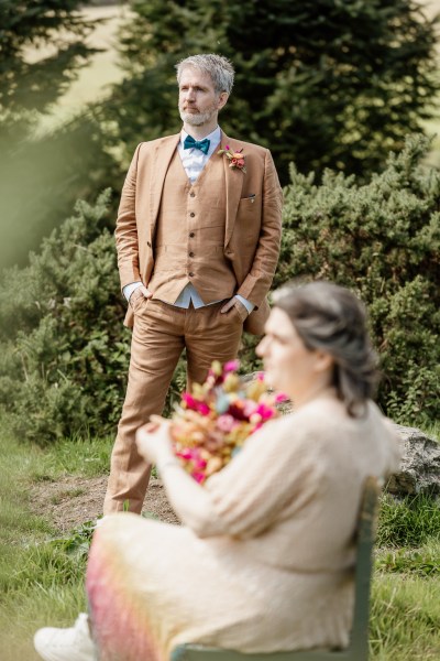 Bride sits in front of groom standing