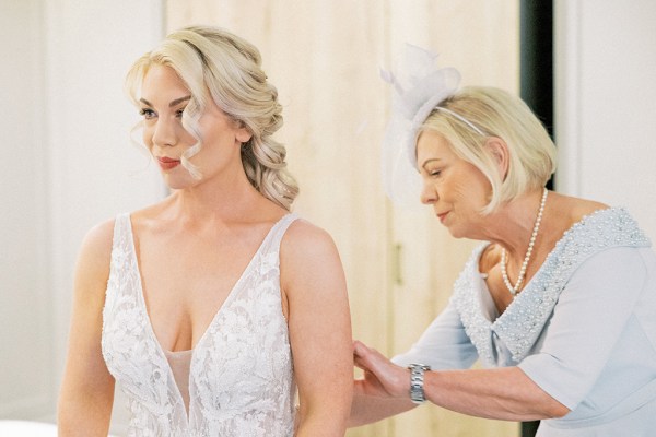 Bride gets help from mother zipping up back of dress