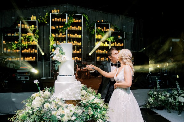 Bride and groom cutting the white wedding cake together