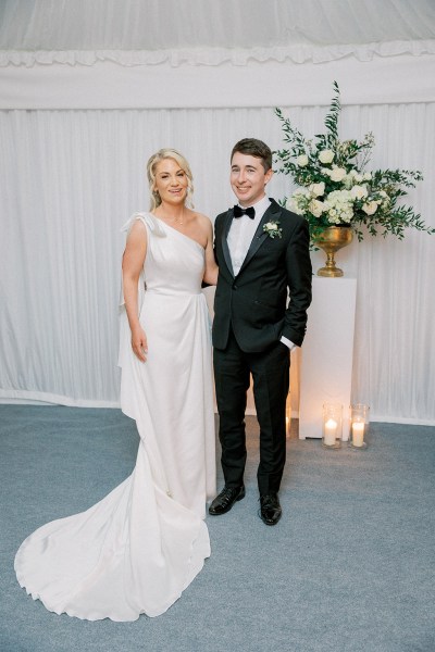 Bride and groom pose in front of statue flowers