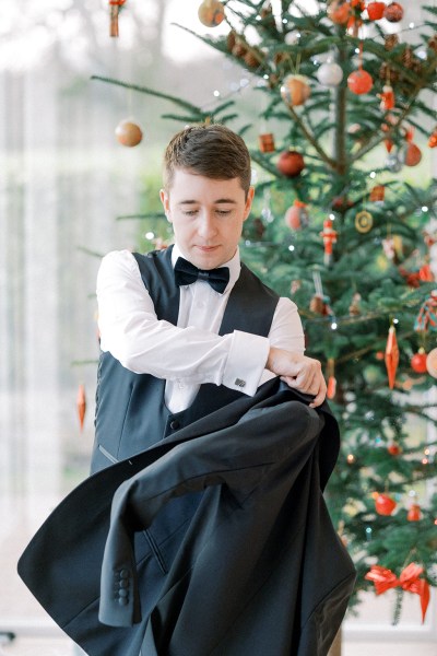 Groom puts on his black suit jacket