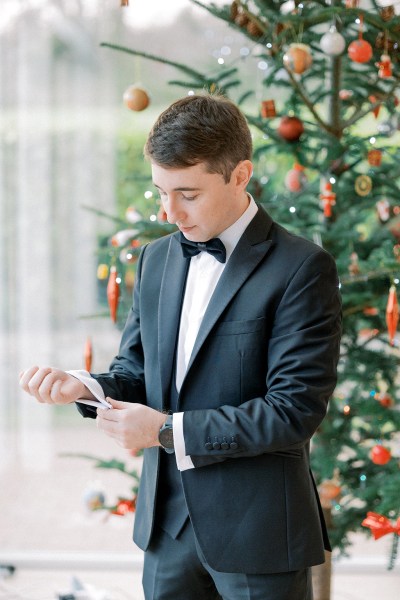 Groom puts on his black suit jacket and fixes the arms and cufflinks