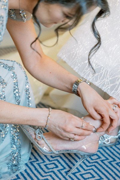 Bridesmaid helps bride with bridal heels/shoes