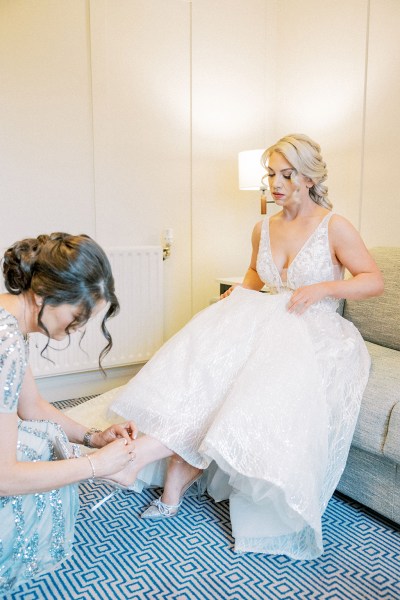 Bridesmaid helps bride with bridal heels/shoes