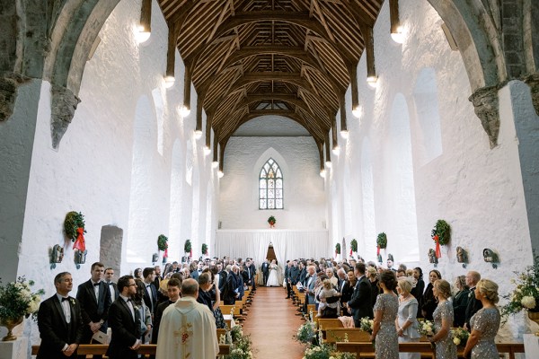 Ceremony interior church guests seated and priest in shot