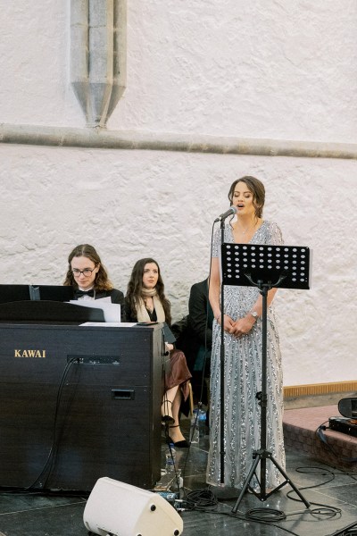 Opera singer sings into microphone while piano is playing