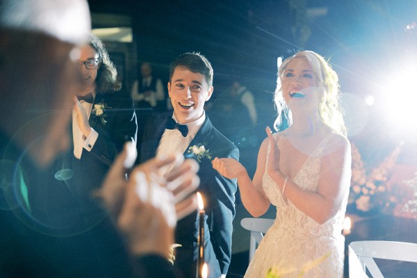 Bride and groom smile and react by clapping