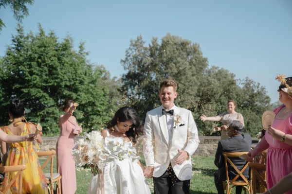 Bride and groom exit ceremony guests clapping she holds bouquet