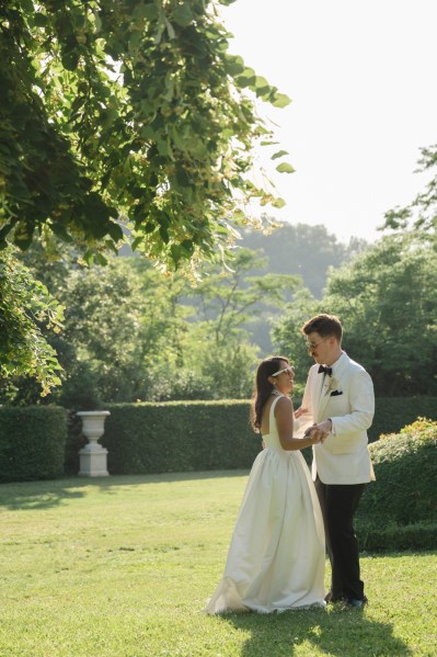 Couple bride and groom wear sunglasses standing on the grass hold each other and look at each other