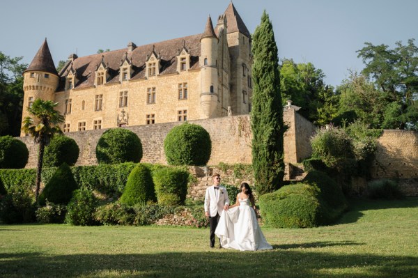 Couple walk along the grass outside castle venue