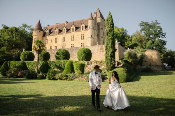 Couple walk along the grass outside castle venue