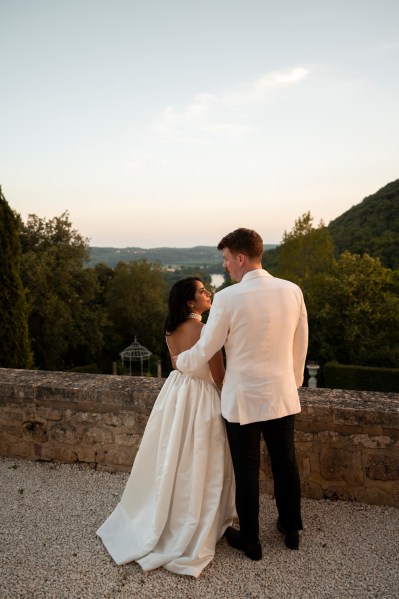 Bride and groom overlook scenery trees mountains from behind