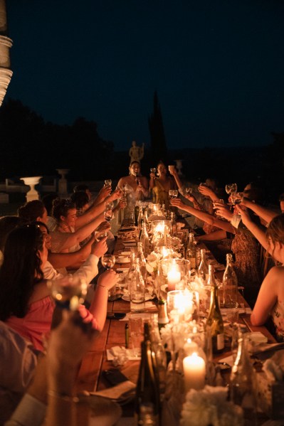 Nighttime shot of guests cheers over table candles