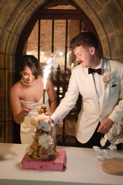 Bride groom bowtie sparkler in background and white roses cake