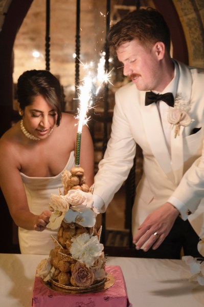 Bride groom bowtie sparkler in background and white roses cake