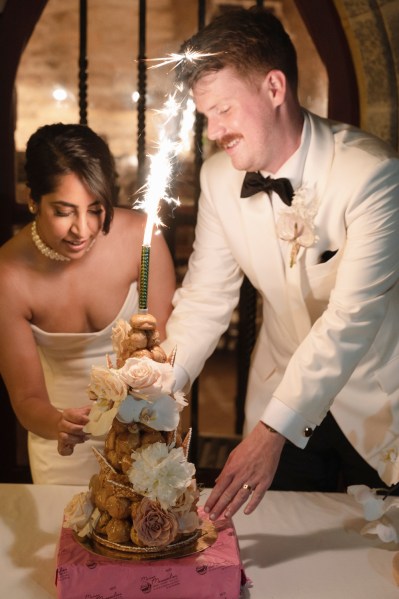 Bride groom bowtie sparkler in background and white roses cake