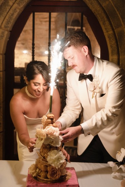 Bride groom bowtie sparkler in background and white roses cake