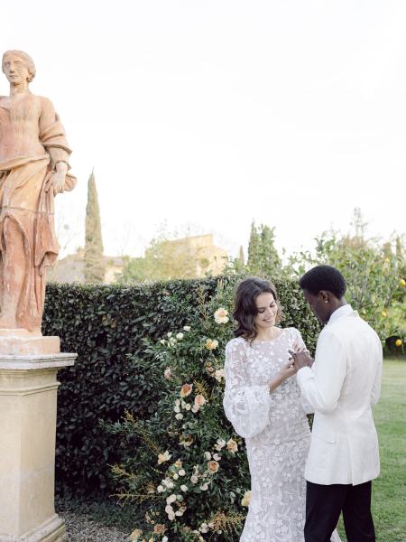 Bride looks at groom laughing smiling statue in view