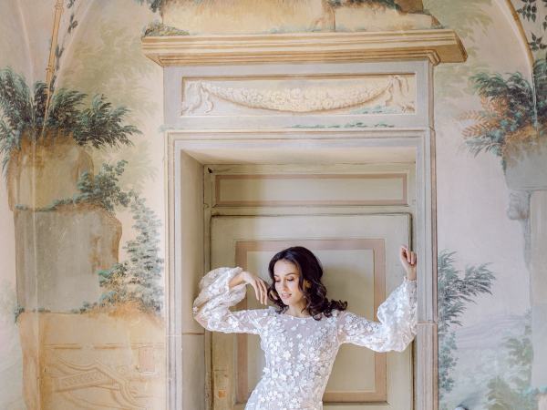 bride in lace gown posing in front of painting decor canvas in front of door