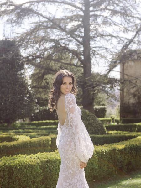 Bride stands in garden looking over shoulder lace gown dress