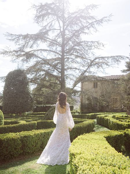 shot of bride from behind walking on pathway to garden facing away