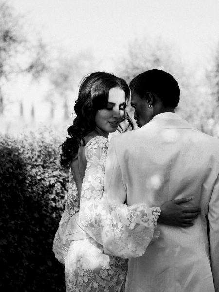 Bride puts her hand on grooms back black and white smiling