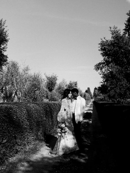 Black and white bride and groom touch foreheads in park garden