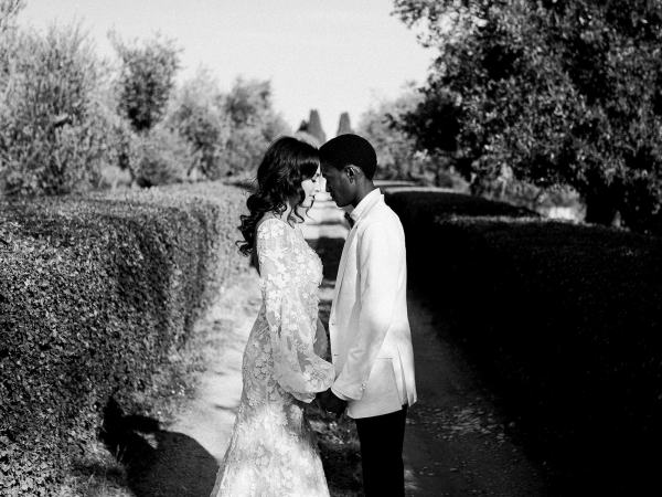 Black and white bride and groom touch foreheads in park garden