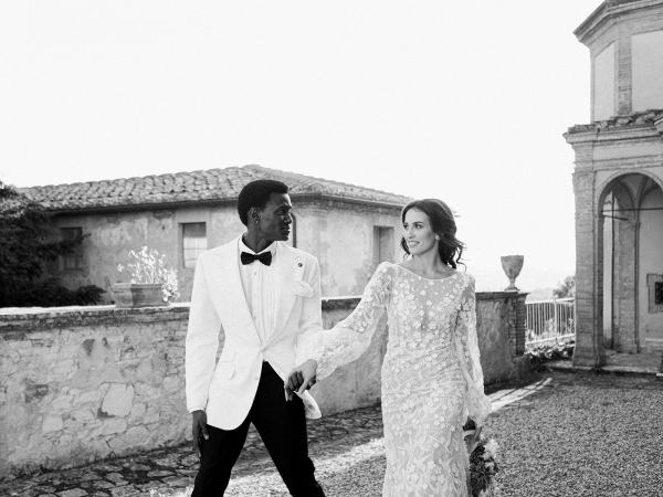 Bride and groom walk hand in hand in garden black and white