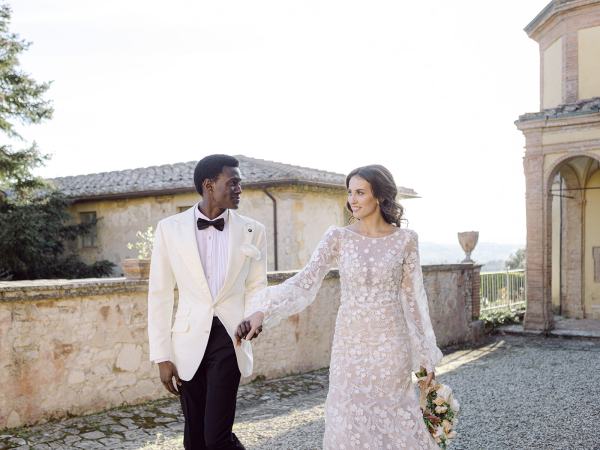 Bride and groom walk hand in hand in garden