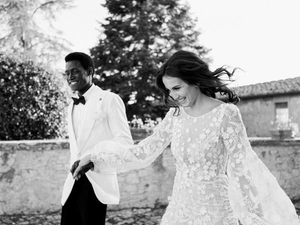 Bride and groom walk hand in hand in garden at venue black and white