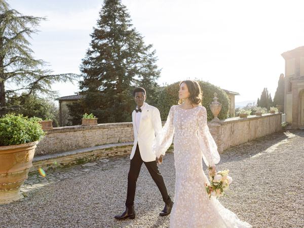 Bride and groom walk hand in hand in garden