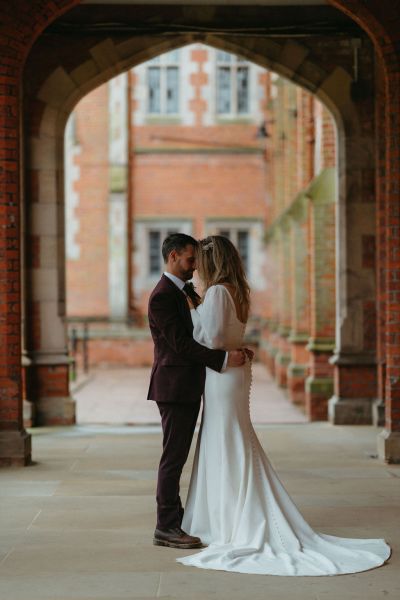 Bride and groom pose under archway together at Queen's University