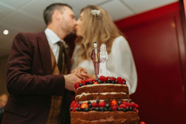 Bride and groom smile laugh strawberry wedding cake on table