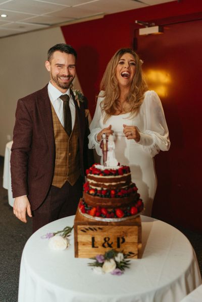 Bride and groom smile laugh strawberry wedding cake on table