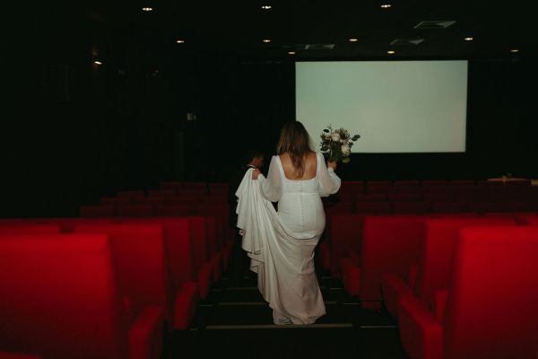 Bride walks down carrying her dress and bouquet down the aisle