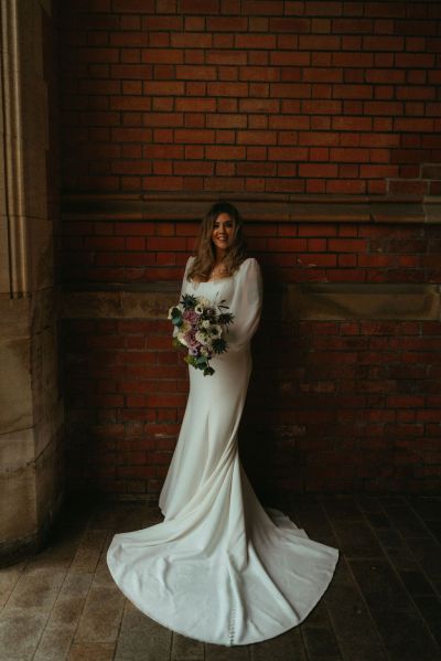 Dimly dark lit bride stands under archway