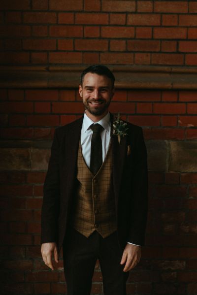 Groom darkly dimly lit smiles for the camera