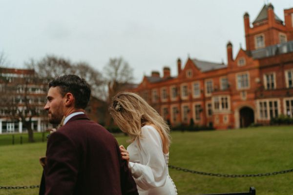 Bride and groom walking outside wedding venue grass area