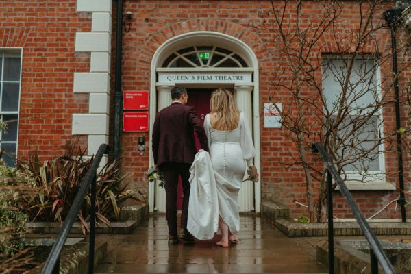 Bride and groom from behind walking towards wedding ceremony venue