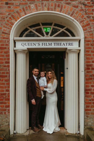 Bride groom and little baby girl outside ceremony building