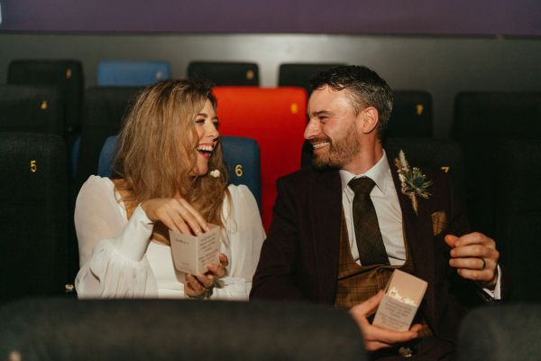 Bride and groom laugh together in wedding car