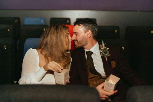 Bride and groom touch noses going in for a kiss in wedding car